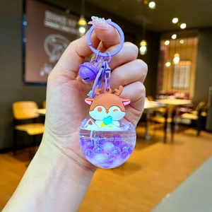 Close-up of a purple deer keychain with liquid glitter inside a clear dome charm