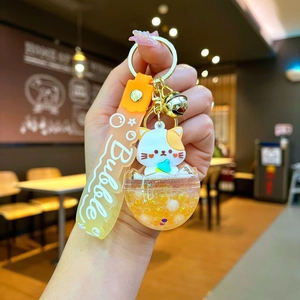 Detail of cute cat liquid keychain with orange flowing glitter and gold bell charm