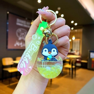 Detailed shot of a blue penguin keychain with bubble tea liquid element and a gold ring