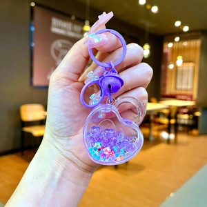 Close-up of purple heart-shaped liquid glitter keychain with tiny flowers and star sequins