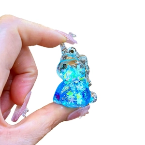 Miniature blue transparent unicorn charm with glitter and snow sequins on white background