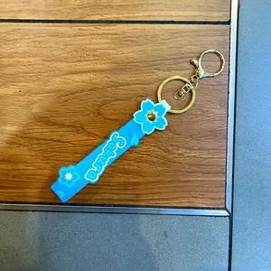 Blue silicone Sakura keychain with floral charms and golden metal clip on wood surface