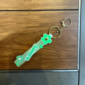 Detail of green Sakura PVC wristlet strap with golden metal clasp on a wooden background