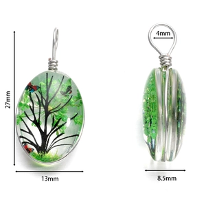 Pendentif ovale en verre fait main avec fleurs séchées vertes et arbre de vie sur blanc