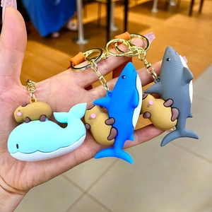 Capybara dressed as shark and whale silicone keychains being held in hand