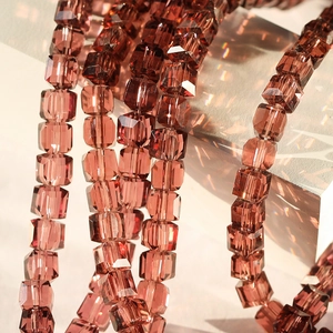 Macro detail of 8mm faceted wine red crystal glass cube beads with light refraction