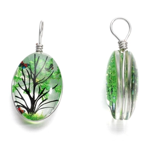 Détail de pendentifs ovales en résine arbre de vie avec fil d'argent et feuilles vertes