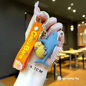 Detail view of cartoon Capybara keychain with blue shark hat and orange silicone strap