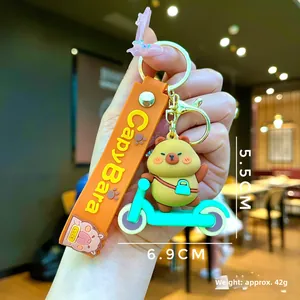 Detail of Capybara keychain on a green scooter with orange strap and dimensions