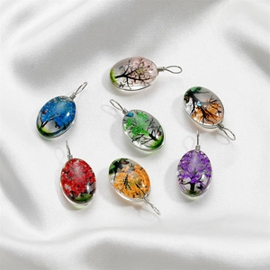 Détail de pendentifs arbre de vie faits main en verre coloré sur de la soie blanche