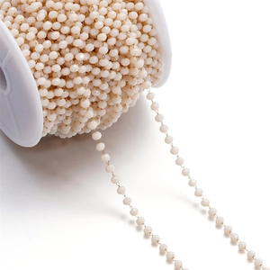 Macro shot of 3mm pink faceted crystal bead chain on white spool for DIY jewelry