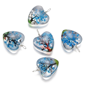 Gros plan de pendentifs en verre en cœur avec arbre de vie et fleurs bleues