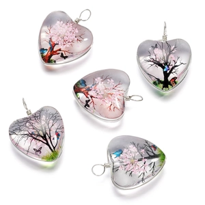 Détail de cinq pendentifs en verre en forme de cœur avec arbre de vie et papillons