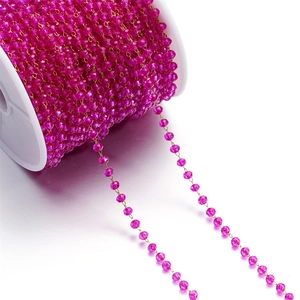 Macro shot of faceted fuchsia beads on golden wire chain for DIY jewelry making