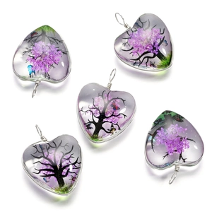 Vue détaillée de pendentifs en verre en forme de cœur avec fleurs séchées et arbre de vie