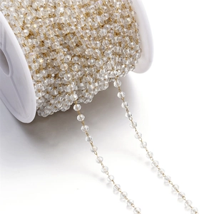 Detail of 3mm transparent faceted crystal beads linked by gold-plated chain on spool