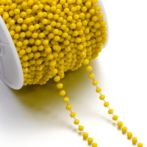 Macro detail of 3mm yellow faceted crystal bead chain on a spool for DIY jewelry making