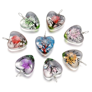 Détails de motifs d'arbre de vie colorés dans des pendentifs en verre en forme de cœur