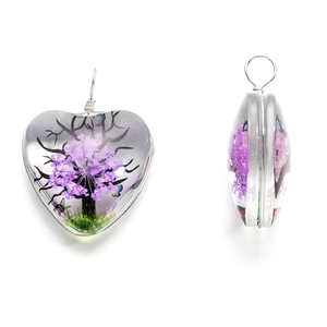 Détail du pendentif en verre en cœur avec fleurs séchées mauves et fil d'argent