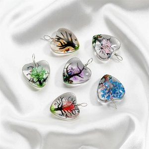 Détail de six pendentifs en verre en forme de cœur avec l'arbre de vie et fleurs séchées
