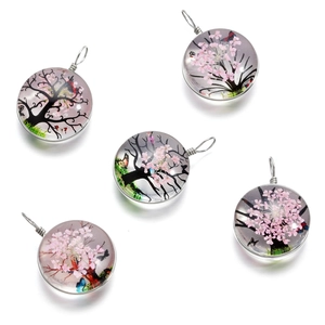 Détail de pendentifs ronds en verre arbre de vie avec fleurs séchées et fil métal