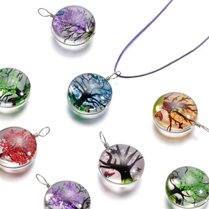 Détail de pendentifs en verre faits main avec motifs d'arbre de vie en fleurs séchées