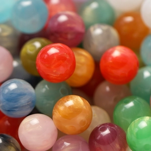 Nahaufnahme bunter Harzperlen mit Marmorierung und Perlglanzeffekt für DIY-Schmuck