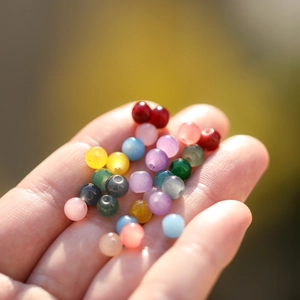 Perles en verre translucides colorées pour bijoux DIY présentées dans la main