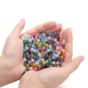 Gros plan de perles en verre translucide coloré tenues en main pour bijoux DIY