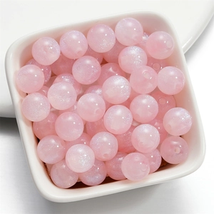 Primo piano di perle in resina a sirena rosa con glitter cangianti in un piatto di ceramica