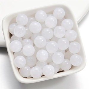 Dettaglio macro di perle in resina bianco perlato con finitura brillante in un piatto
