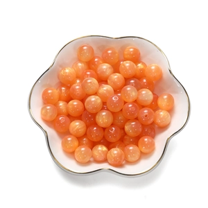 Makro-Detail von orangefarbenen Harzperlen mit Wolkenmarmorierung in einer Keramikschale
