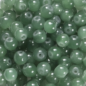 Vue macro de perles rondes en verre poli vert forêt avec trous pour la création de bijoux