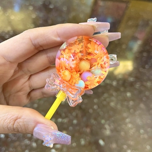 Dettaglio portachiavi a lecca-lecca arancione con sabbie mobili, glitter e fiocchetto