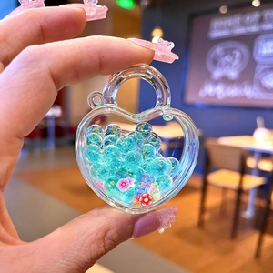 Detail of heart-shaped acrylic charm with blue beads and sequins for bag accessory
