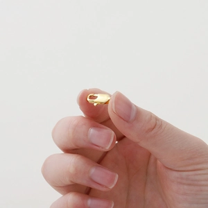 Makroaufnahme von 18k vergoldetem Karabinerverschluss für DIY-Schmuckherstellung am Finger