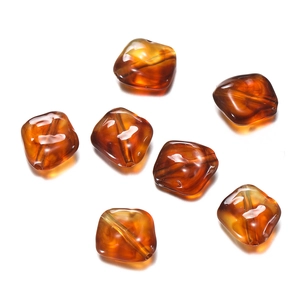 Macro detail of seven amber acrylic irregular polygon beads for DIY phone chain making