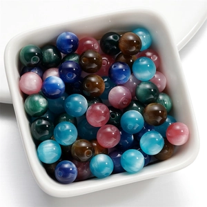 Detailed view of colorful resin cat-eye beads in a white tray for DIY jewelry making