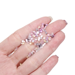 Macro detail of tiny macaron colored tube beads held in palm for DIY jewelry crafting
