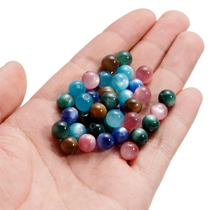 Close-up of colorful 6mm cat-eye resin beads held in hand for DIY jewelry making
