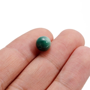Detailed view of a dark green resin bead on a finger for scale and size reference