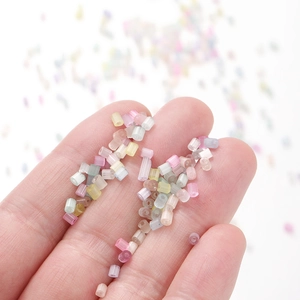 Mix of colorful 2mm frosted macaron glass seed beads held in hand for DIY jewelry making
