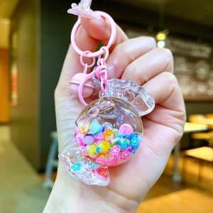 Close-up of candy-shaped keychain with colorful beads, pink bell, and bow accessory