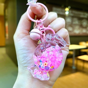 Detail of pink candy-shaped keychain with flowing sand and small floral glitter charms