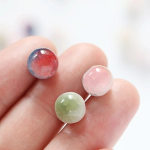 Macro shot of 10mm frosted glass beads in pink, green, and gradient blue on fingertips