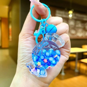 Close-up of a blue candy-shaped keychain with flowing beads, a bell, and a lobster clasp