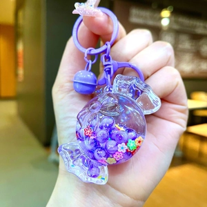 Detailed close-up of a purple candy-shaped keychain with beads and a bell charm