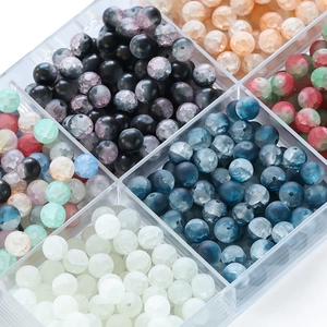 Close-up of 10mm frosted ice-crack glass beads in a clear storage organizer for jewelry DIY