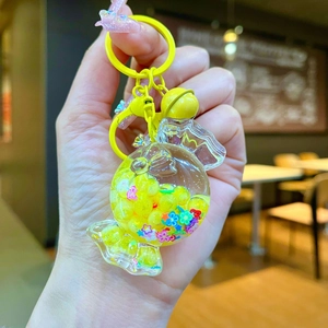 Detail of yellow candy-shaped keychain with luminous quicksand beads and a small bell