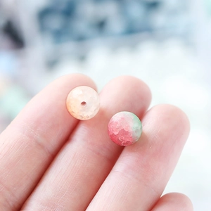 Macro view of 10mm frosted ice-crack glass beads for DIY jewelry held on fingertips